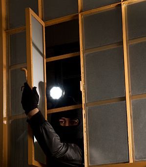 hacker breaking into a house window
